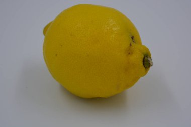 Ürünler, sağlıklı ve sağlıklı yiyecekler, taze meyveler. Olgun sulu sarı limon beyaz plastik arka planda yer alır..