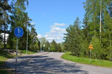 Finlandiya 'nın Espoo şehrinde güzel caddeler, otoyollar, yollar ve rotalar manzarası vardır. Girişleri olan güzel özel evler, yeşil çimenler, çalılar, yeşil yapraklı ağaçlar, kaldırım boyunca büyüyen ince köknarlar, yollar..