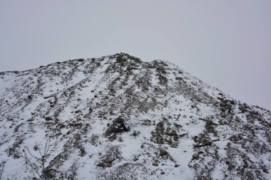 Parlak, güzel doğa, kışın dondurucu hava. Büyük tepeler, yoğun beyaz karla kaplı keskin dağlar. Yüksek tepe, yüksek dağ ve ağaçların yanından geçen dolambaçlı bir yol..