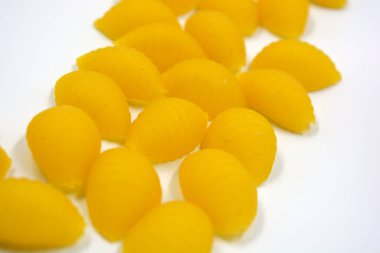 Kuru sarı İtalyan vermicelli, katı tahıl çeşitleri deniz kabuğu şeklinde yapılmış makarna beyaz arka planda yer almaktadır..