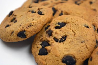 Beyaz arka planda çikolata parçalı büyük, lezzetli bir kurabiye..