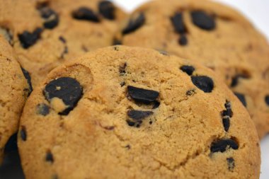 Beyaz arka planda çikolata parçalı büyük, lezzetli bir kurabiye..