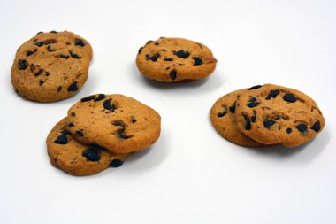 Beyaz arka planda çikolata parçalı büyük, lezzetli bir kurabiye..