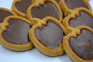 İçinde fındıklı, çikolatalı kurabiyeler olan taze, lezzetli çıtır kurabiyeler. Beyaz bir arka planda kahverengi dolgulu elma şekilli kurabiyeler.