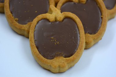 İçinde fındıklı, çikolatalı kurabiyeler olan taze, lezzetli çıtır kurabiyeler. Beyaz bir arka planda kahverengi dolgulu elma şekilli kurabiyeler.