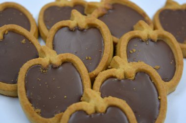 İçinde fındıklı, çikolatalı kurabiyeler olan taze, lezzetli çıtır kurabiyeler. Beyaz bir arka planda kahverengi dolgulu elma şekilli kurabiyeler.