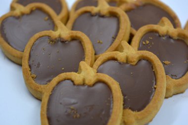 İçinde fındıklı, çikolatalı kurabiyeler olan taze, lezzetli çıtır kurabiyeler. Beyaz bir arka planda kahverengi dolgulu elma şekilli kurabiyeler.