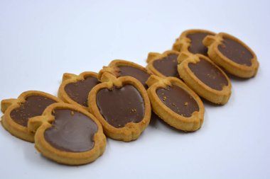 İçinde fındıklı, çikolatalı kurabiyeler olan taze, lezzetli çıtır kurabiyeler. Beyaz bir arka planda kahverengi dolgulu elma şekilli kurabiyeler.