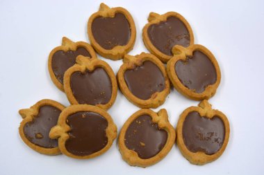 İçinde fındıklı, çikolatalı kurabiyeler olan taze, lezzetli çıtır kurabiyeler. Beyaz bir arka planda kahverengi dolgulu elma şekilli kurabiyeler.