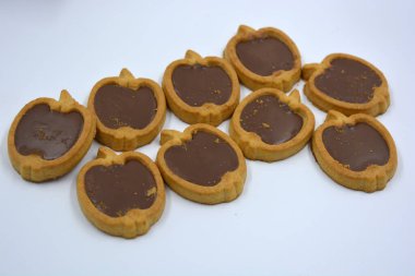 İçinde fındıklı, çikolatalı kurabiyeler olan taze, lezzetli çıtır kurabiyeler. Beyaz bir arka planda kahverengi dolgulu elma şekilli kurabiyeler.