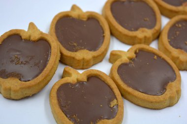 İçinde fındıklı, çikolatalı kurabiyeler olan taze, lezzetli çıtır kurabiyeler. Beyaz bir arka planda kahverengi dolgulu elma şekilli kurabiyeler.