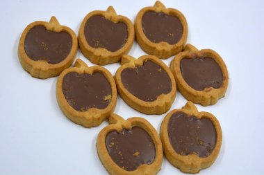 İçinde fındıklı, çikolatalı kurabiyeler olan taze, lezzetli çıtır kurabiyeler. Beyaz bir arka planda kahverengi dolgulu elma şekilli kurabiyeler.