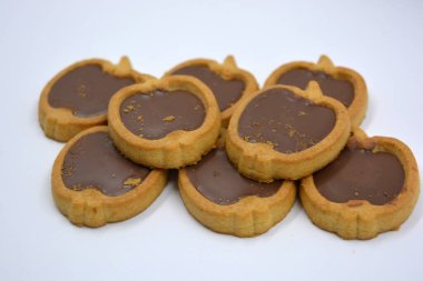 İçinde fındıklı, çikolatalı kurabiyeler olan taze, lezzetli çıtır kurabiyeler. Beyaz bir arka planda kahverengi dolgulu elma şekilli kurabiyeler.