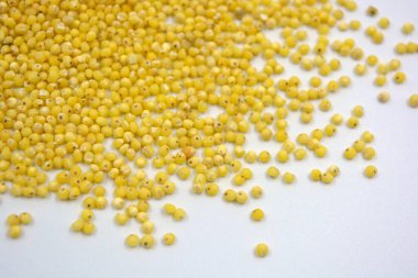 Çok sağlıklı ve kullanışlı homurtular, beyaz bir arka plana saçılmış sarı darılar. Bu mısır gevreğindeki yulaf lapası vücuttaki toksinleri temizler..