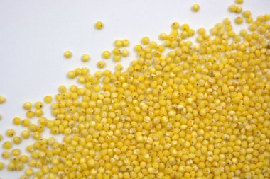 Çok sağlıklı ve kullanışlı homurtular, beyaz bir arka plana saçılmış sarı darılar. Bu mısır gevreğindeki yulaf lapası vücuttaki toksinleri temizler..