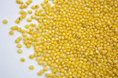 Çok sağlıklı ve kullanışlı homurtular, beyaz bir arka plana saçılmış sarı darılar. Bu mısır gevreğindeki yulaf lapası vücuttaki toksinleri temizler..