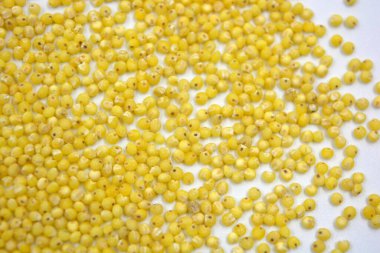 Çok sağlıklı ve kullanışlı homurtular, beyaz bir arka plana saçılmış sarı darılar. Bu mısır gevreğindeki yulaf lapası vücuttaki toksinleri temizler..