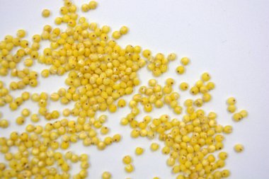 Çok sağlıklı ve kullanışlı homurtular, beyaz bir arka plana saçılmış sarı darılar. Bu mısır gevreğindeki yulaf lapası vücuttaki toksinleri temizler..