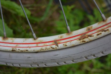 Eşyalar, eşyalar, spor, sağlık. Eski bir kırmızı metal bisiklet yeşil bir çimenlikte beyaz bir çite karşı duruyor. Bisiklet parçaları eski, bisiklet tekerlekleri paslı, bisikletin metal kısımlarında birçok kırmızı pas lekesi var..