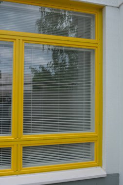 Eşyalar, sarı yüzlü ev, çimenli güzel bir daire. Beyaz panjurları olan büyük sarı plastik pencereler. Güzel, şık dış görünüş, inşaat, onarım.