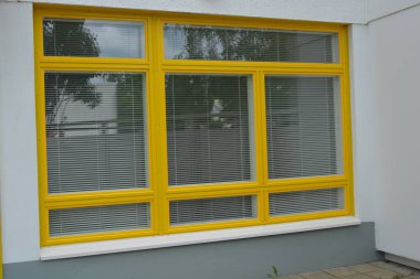 Eşyalar, sarı yüzlü ev, çimenli güzel bir daire. Beyaz panjurları olan büyük sarı plastik pencereler. Güzel, şık dış görünüş, inşaat, onarım.