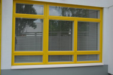 Eşyalar, sarı yüzlü ev, çimenli güzel bir daire. Beyaz panjurları olan büyük sarı plastik pencereler. Güzel, şık dış görünüş, inşaat, onarım.