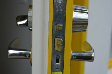 Sıradan günlük şeyler, kapı aksesuarları, metal alaşımlar. Büyük metal saplar, kapı kilitleri, metal mandallar yeni sarı kapının üzerinde..