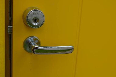 Sıradan günlük şeyler, kapı aksesuarları, metal alaşımlar. Büyük metal saplar, kapı kilitleri, metal mandallar yeni sarı kapının üzerinde..