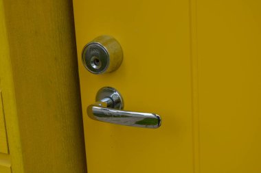 Sıradan günlük şeyler, kapı aksesuarları, metal alaşımlar. Büyük metal saplar, kapı kilitleri, metal mandallar yeni sarı kapının üzerinde..