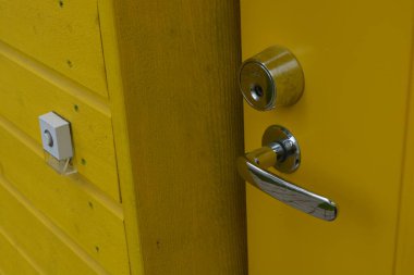 Sıradan günlük şeyler, kapı aksesuarları, metal alaşımlar. Büyük metal saplar, kapı kilitleri, metal mandallar yeni sarı kapının üzerinde..