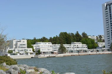 Güzel, parlak doğa, yeşil köknar ağaçları, uzun çam ağaçları, ağaçlar ve güzel beyaz evleri olan tepelik bir manzara. Finlandiya 'nın Espoo şehrinde Finlandiya kıyısında yeni güzel evler bulunmaktadır..