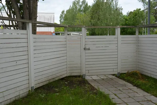 İnşaat, eskrim, bölgeyi komşulardan ve kötü niyetlilerden koruma. Büyük ahşap bir kapısı ve metal bir sapı olan doğal çitten yapılmış parlak, beyaz bir çit..