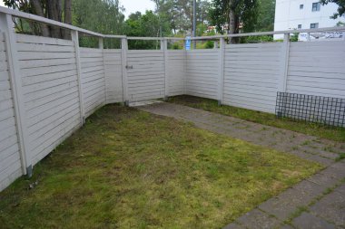 Bina, inşaat, bina. Doğal çam ağacından yapılmış beyaz ahşap çit ve yeşil bir alana sahip beyaz boyayla kaplanmış çimen, beton yollar..