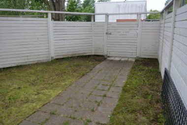 Bina, inşaat, bina. Doğal çam ağacından yapılmış beyaz ahşap çit ve yeşil bir alana sahip beyaz boyayla kaplanmış çimen, beton yollar..