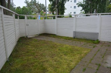 Bina, inşaat, bina. Doğal çam ağacından yapılmış beyaz ahşap çit ve yeşil bir alana sahip beyaz boyayla kaplanmış çimen, beton yollar..