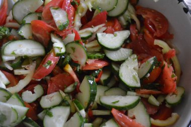 Düzgün, sağlıklı beslenme, sağlıklı sebzeler, salata büyük metal bir kasede bulunur. Dilimlenmiş kırmızı domates, sarı ve kırmızı dolma biber, beyaz soğan, yeşil salatalık ve ekşi sarımsak sosu..