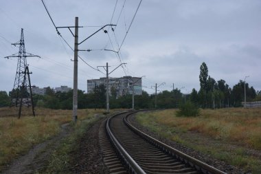 Eski demiryolu rayları, siyah elektrik kablolu metal raylar bozkır boyunca elektrik hatları ve yeşil ağaçlı yeşil orman ve eski çam ağaçları.. 