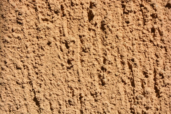 Construction, repair work, lining, covering walls with the latest materials. Brown wide background with voluminous granules, drops, textured sand on the street wall.