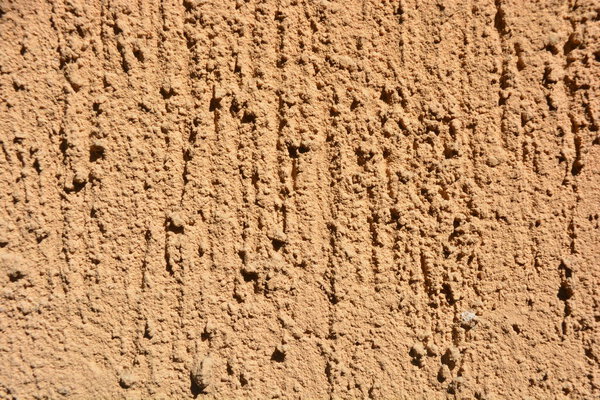 Construction, repair work, lining, covering walls with the latest materials. Brown wide background with voluminous granules, drops, textured sand on the street wall.