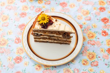 Tabakta yenilebilir çiçeklerle süslenmiş lezzetli bir havuçlu kekin yakın çekimi..