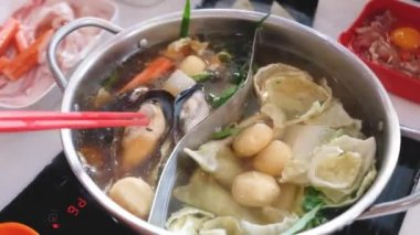 Tencerede et pişirmek için çubuk kullanan bir el. Shabu..