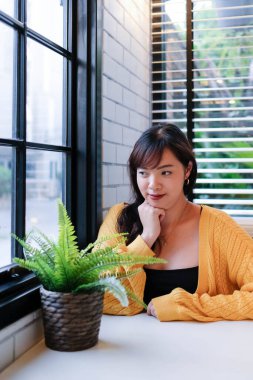 Kafede oturan genç ve güzel Asyalı kadını yakından çek ve rahatla..