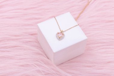 Necklace jewelry, Close up of a heart shape gemstone with a gold chain necklace on pink background. An elegant necklace for valentine's day.