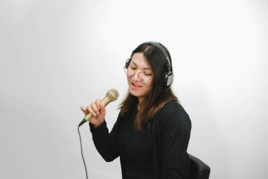 Beautiful asian woman (LGBTQ) is a singer. She enjoying sing a song or karaoke in music studio with microphone condenser and headphones for fun or voice creative clipart