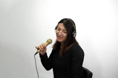 Beautiful asian woman (LGBTQ) is a singer. She enjoying sing a song or karaoke in music studio with microphone condenser and headphones for fun or voice creative clipart