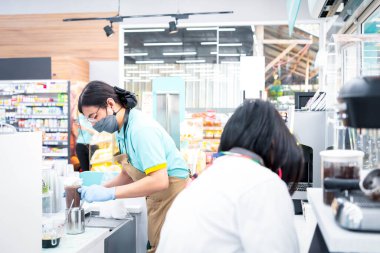 Asyalı kadın, kahve dükkanındaki müşterilere kahve servisi için sütlü kahve fincanına kahve yapmak için kahve köpüğü döken bir barista olarak çalışıyor.