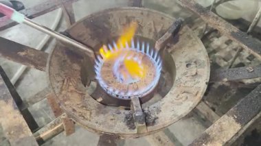 Asyalı aşçı Tayland mutfağında geleneksel taşra tarzında yemek pişiriyor. Klasik bir gaz sobasını elle tutuşturup Tayland yemeği pişirmek için nostaljik bir nostalji hazırlıyor.