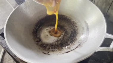 Asyalı aşçı Tayland mutfağında geleneksel köy usulü yemek pişiriyor. Sıcak geleneksel tavada taze yumurta pişirip omlet pişiriyor.