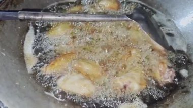 Asyalı aşçı Tayland mutfağında geleneksel taşra usulü yemek pişiriyor. Sıcak tavuklarda pişen köpüklü yağla Tayland yemeği pişiriyor. Cildinde çıtır çıtır.