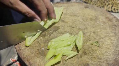 Asyalı aşçı Tayland mutfağında geleneksel köy usulü yemek pişiriyor. Tahta kesme tahtasındaki canlı kırmızı biberleri Tayland yemeği pişirmek için hazırlıyor.